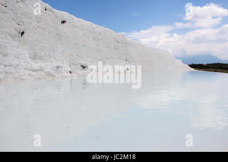 Una vista del travertino dal lato, la più famosa attrazione turistica della Turchia, bianco depositi di calcio sullo sfondo del cielo blu Foto Stock