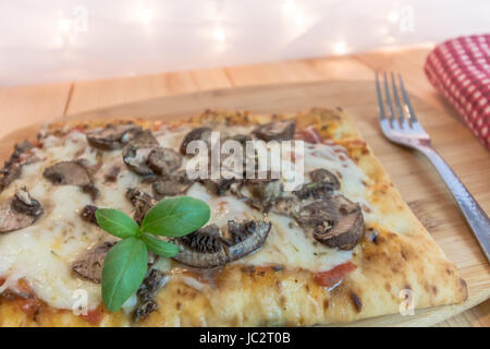 In casa pane piatto veggie pizza con il formaggio, con i funghi e il basilico fresco sulla tavola di legno Foto Stock