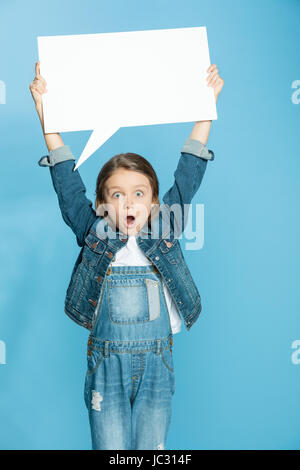 Scioccato bambina azienda vuoto discorso bolla su blu Foto Stock