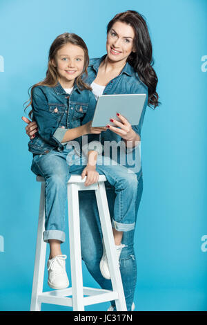 Felice madre e figlia con tavoletta digitale in studio su blu Foto Stock
