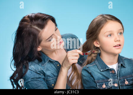 Ritratto di felice madre figlia di treccia di capelli in studio su blu Foto Stock