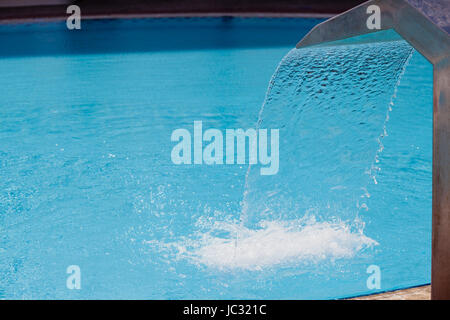 Getto a cascata e texture di acqua che cade sullo sfondo di acqua turchese in piscina Foto Stock