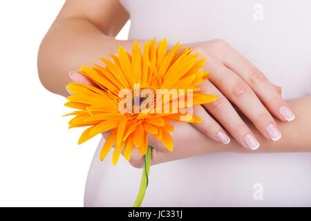 Le mani di una donna incinta con una french manicure e fiore Foto Stock