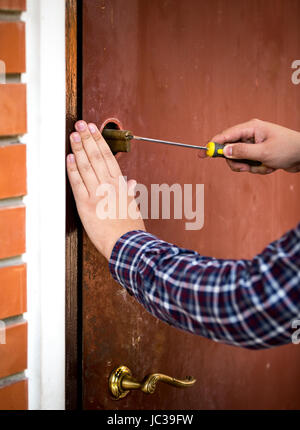 Closeup colpo di falegname che fissa la serratura della porta con un cacciavite Foto Stock