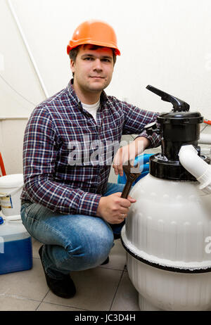 Giovani plumber ponendo al nuovo sistema di pompaggio con strumenti Foto Stock