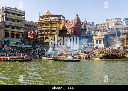 Fumo di cremato corpi morti è in aumento a Manikarnika Ghat presso il fiume sacro Gange nel sobborgo Godowlia Foto Stock