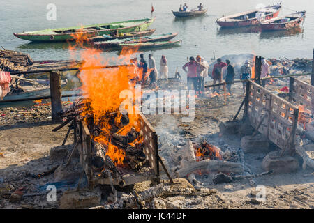 Fumo di cremato corpi morti è in aumento a manikarnika ghat presso il fiume sacro Gange nel sobborgo godowlia Foto Stock