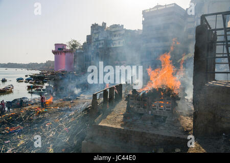 Fumo di cremato corpi morti è in aumento a manikarnika ghat presso il fiume sacro Gange nel sobborgo godowlia Foto Stock