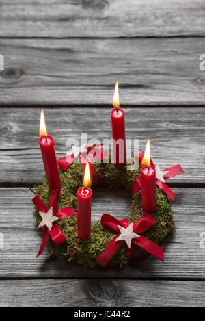 Biglietto di auguri con quattro red burning avvento candele di legno su sfondo grigio. Foto Stock