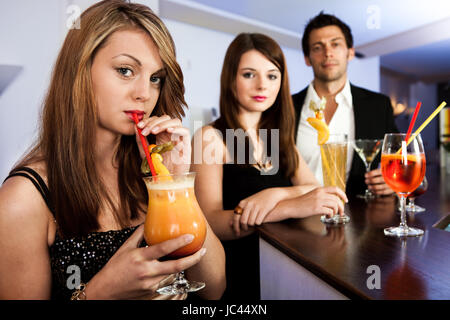 Belle Donne con gli amici al bar. Bere tequila sunrise Foto Stock