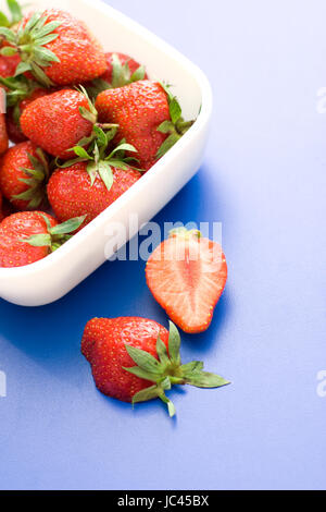 Due pezzi di mezza fragola nella parte anteriore di una piastra piena Foto Stock