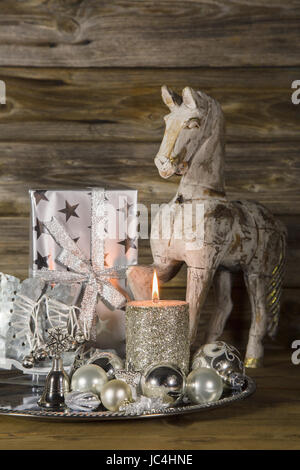 Naturale natale decorazione in argento e marrone con il cavallo e la candela su sfondo di legno. Foto Stock