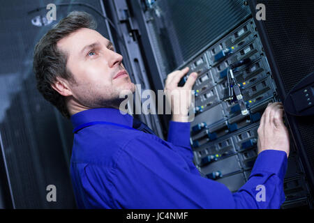 Smart fiducioso uomo in piedi di fronte sul server dei dati Foto Stock