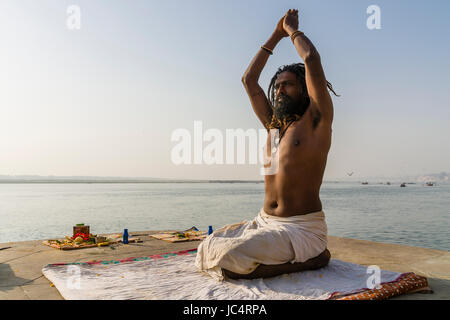 Un sadhu, uomo santo, è la pratica dello Yoga asana su una piattaforma presso il fiume sacro Gange a meer ghat nel sobborgo godowlia Foto Stock