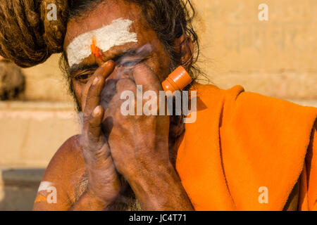 Ritratto di un sadhu, uomo santo, fumare marijuana presso il fiume sacro Gange a dashashwamedh ghat, principale ghat, nel sobborgo godowlia Foto Stock