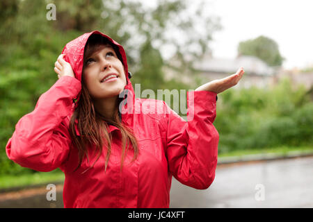 Bella donna nel controllo di un impermeabile per la pioggia Foto Stock