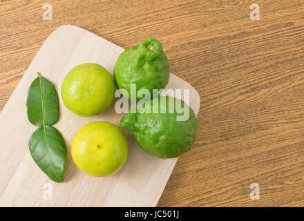 Vegetali e le erbe, vista dall'alto di fresco e verde lime Kaffir con persiano di lime e foglie di Kaffir per la stagionatura in cottura su una tavola di legno con copia Spac Foto Stock