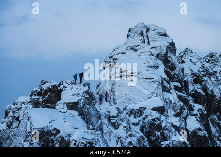 Gli escursionisti stand sul ripido crinale nevoso vicino Tatind, VestvÃ¥gÃ'y, Isole Lofoten in Norvegia Foto Stock