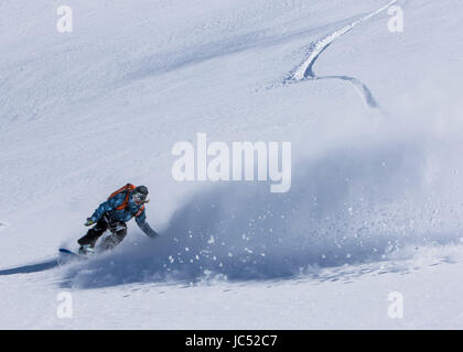 Professional Snowboarder Robin Van Gyn, giostre di polvere fresca in una giornata di sole mentre lo snowboard in Haines, Alaska. Foto Stock