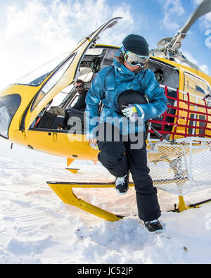 Professional Snowboarder Robin Van Gyn, fuoriesce da un elicottero per snowboard una linea durante un viaggio a Haines, Alaska. Foto Stock