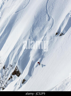 Professional Snowboarder Marie Francia Roy, corse di polvere fresca in una giornata di sole mentre lo snowboard in Haines, Alaska. Foto Stock