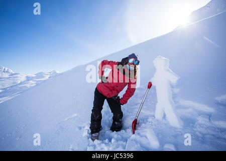 Professional Snowboarder Marie Francia Roy, appeso fuori con un uomo di neve scolpiti dal vento duro strato sulla superficie in una giornata di sole in Haines, Alaska. Foto Stock