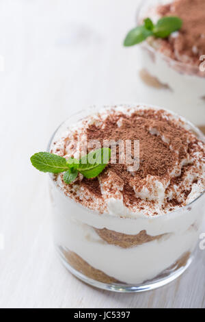 Classico dolce italiano tiramisù servito in bicchieri su sfondo bianco Foto Stock