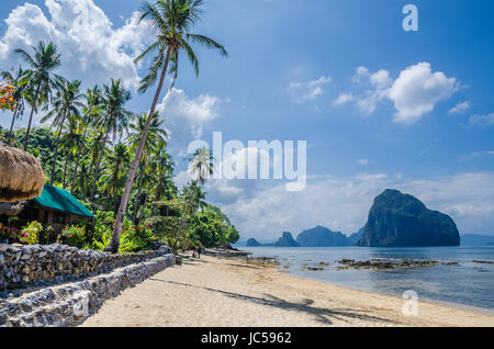 Marimegmeg soleggiata spiaggia di bassa marea in El Nido, bar sotto le palme di fronte, PALAWAN FILIPPINE Foto Stock