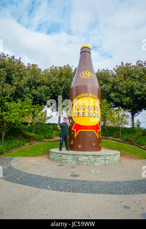 AUCKLAND, NUOVA ZELANDA - 16 Maggio 2017: un uomo non identificato in posa accanto al limone e paeroa bottiglia gigante scultura, Nuova Zelanda. Foto Stock