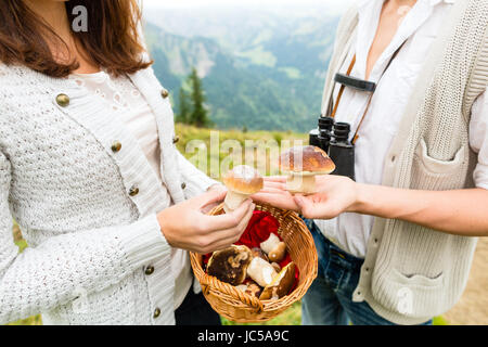 Funghi - coppia giovane cerca e ricerca di funghi porcini in montagna Foto Stock