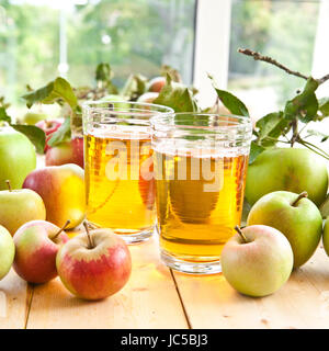 Klarer Apfelsaft in Glaesern mit frischen Aepfeln Foto Stock