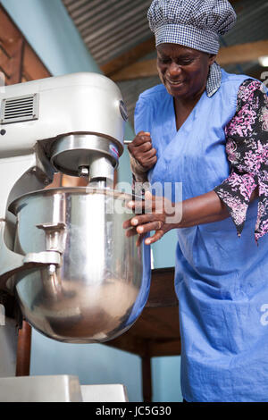 Una femmina di baker usando il suo cibo mixer per fare il pane. TANZANIA, AFRICA. Foto Stock