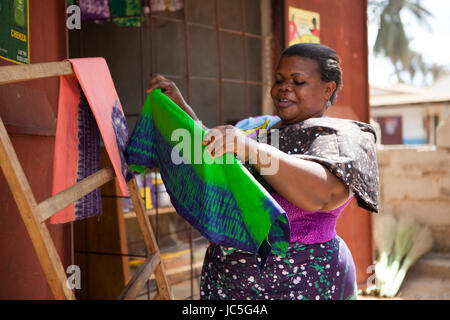 Una femmina di batik proprietario del negozio espone il suo tessuto, Tanzania, Africa. Foto Stock