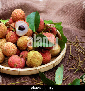 Close up di litchi frutto o lychee frutti, un'agricoltura tropicale prodotto a Luc Ngan, Bac Giang, Vietnam, cesto di Vai thieu su sfondo marrone Foto Stock