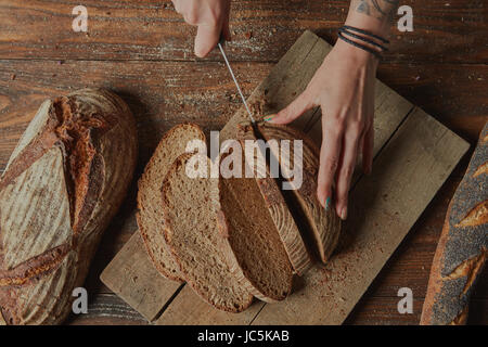 Il panettiere di crusca per affettare il pane su un tagliere laici piatta Foto Stock