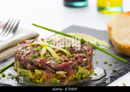 Il tonno rosso tartare di tonno su un nero ardesia piastra con avocado, servita con pane grigliato. Foto Stock