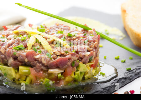 Il tonno rosso tartare di tonno su un nero ardesia piastra con avocado, servita con pane grigliato. Foto Stock