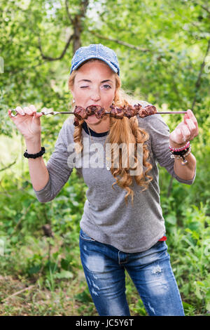 Donna mangia la carne e winks Foto Stock