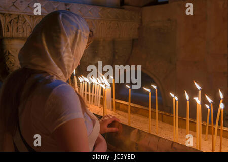 Donna con capelli coperta dicendo una preghiera nella chiesa del Santo Sepolcro, situato nel Quartiere Cristiano della Città Vecchia di Gerusalemme, Israele. Foto Stock