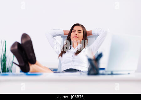 Giovane imprenditrice rilassante in ufficio Foto Stock