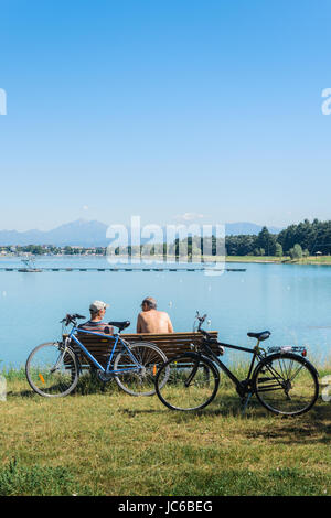 Due uomini anziani seduti su una panchina nel parco dopo la mountain bike in Idroscalo, Milano, Italia Foto Stock