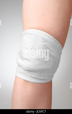 Ferite dolorose ginocchio con bianco Benda di garza Foto Stock