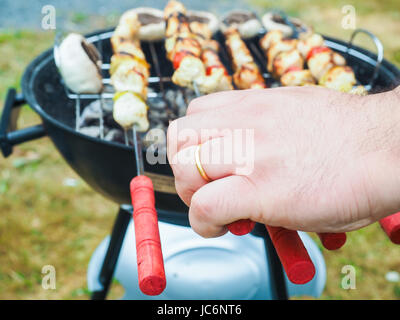 Primo piano di una persona alla brace shish con pollo e verdure Foto Stock