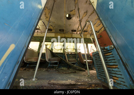 Ridotto in schegge e sedi di pelatura coperto di detriti all'interno abbandonato trolley car. Foto Stock