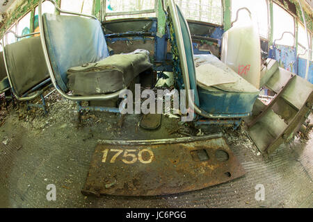 Posti a sedere coperti di detriti all'interno abbandonato trolley car. Foto Stock