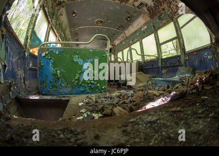 Ridotto in schegge e sedi di pelatura coperto di detriti all'interno abbandonato trolley car. Foto Stock