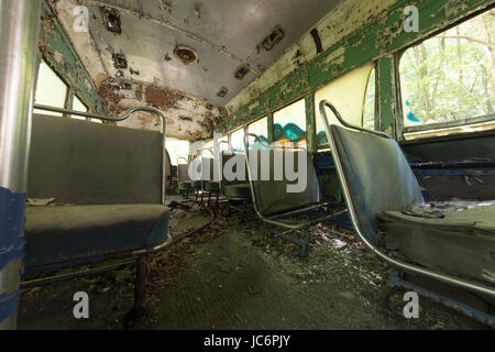 Ridotto in schegge e sedi di pelatura coperto di detriti all'interno abbandonato trolley car. Foto Stock