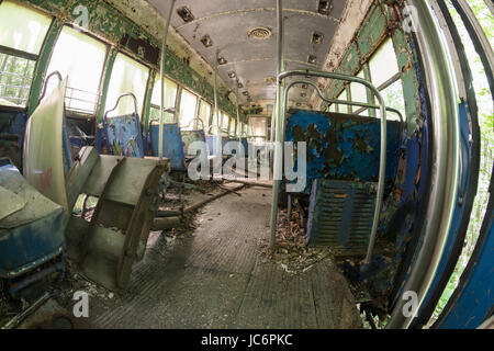 Ridotto in schegge e sedi di pelatura coperto di detriti all'interno abbandonato trolley car. Foto Stock