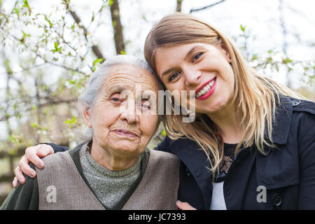 Fotografia di una donna anziana con allegro caregiver all'aperto nel giardino, primavera Foto Stock