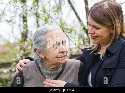 Fotografia di una donna anziana con allegro caregiver all'aperto nel giardino, primavera Foto Stock